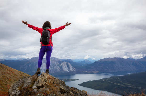 Woman hiking on top of a mountain looking at a river below