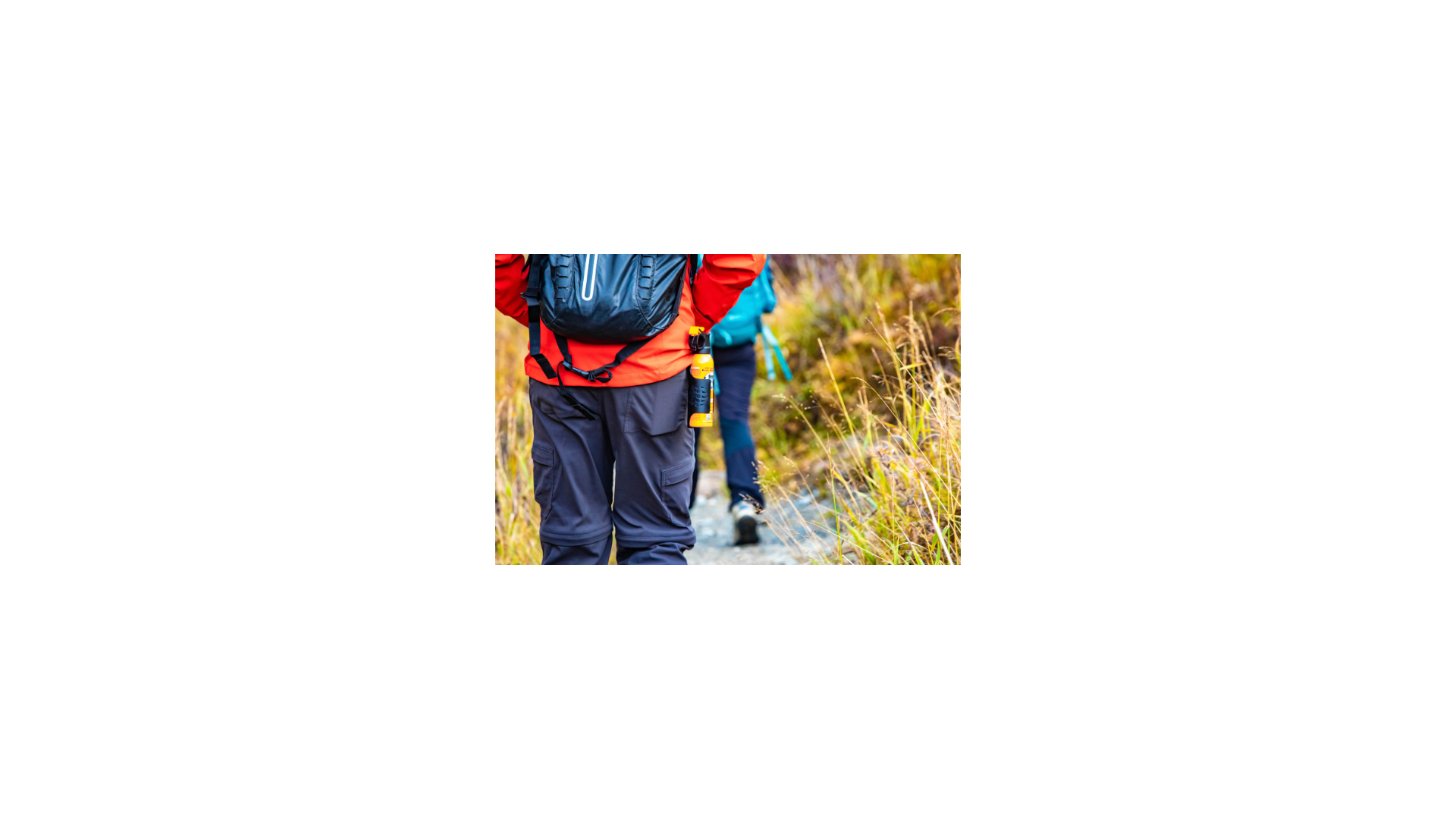 A person hiking with a can of bear spray attached to their hip