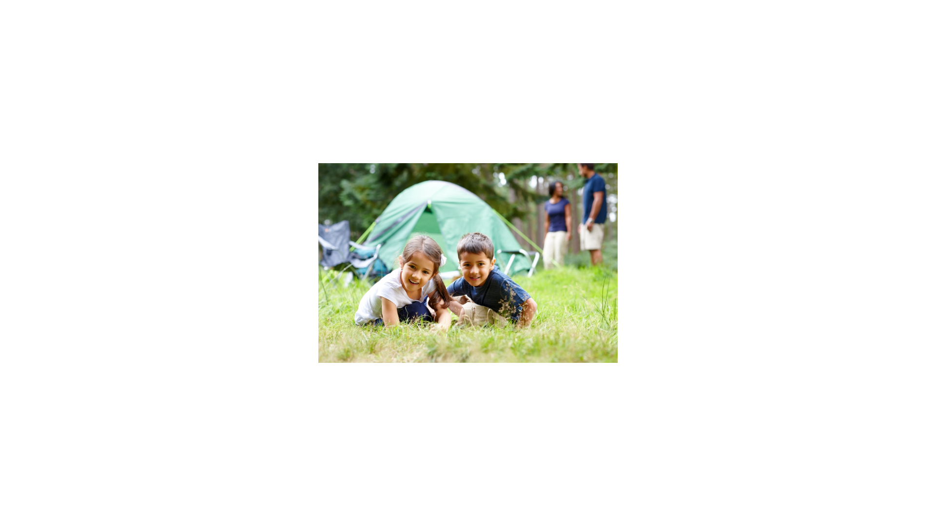 two children sitting in the grass in front of a tent