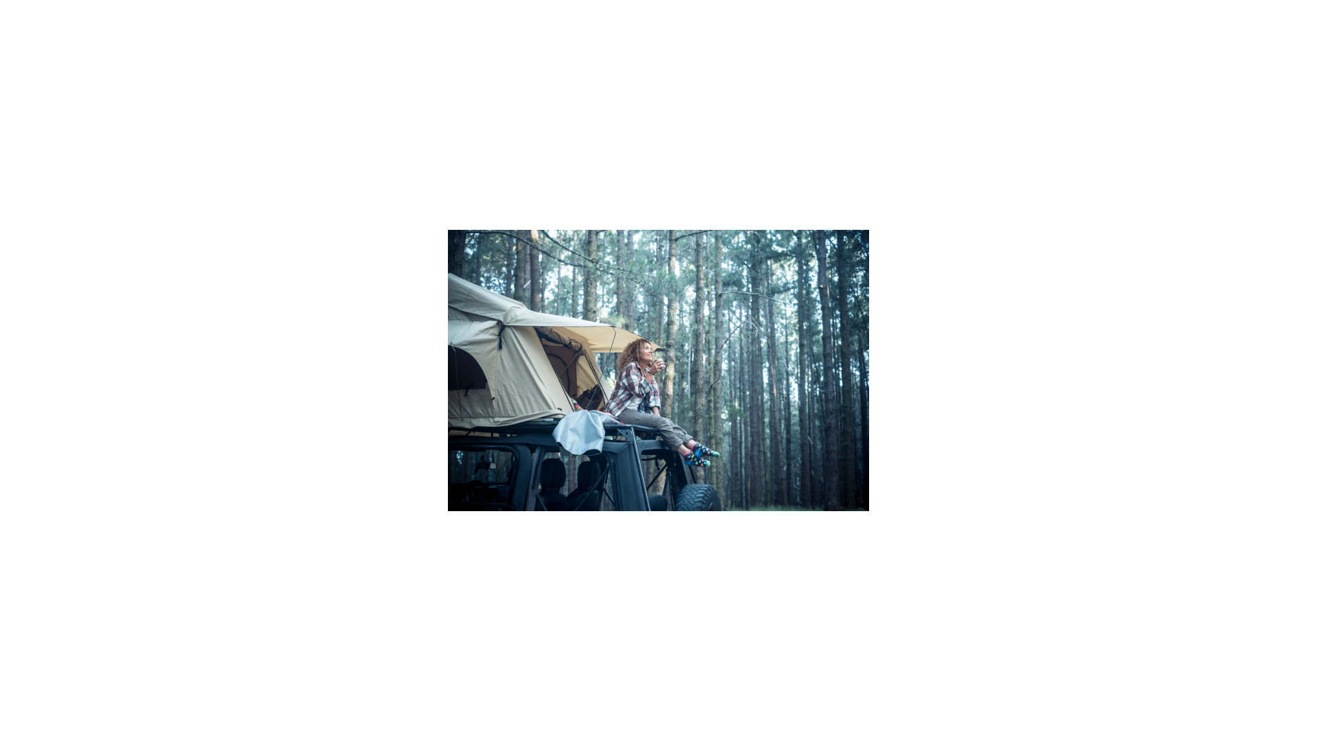 Lady sitting on rooftop tent, on top of vehicle. 