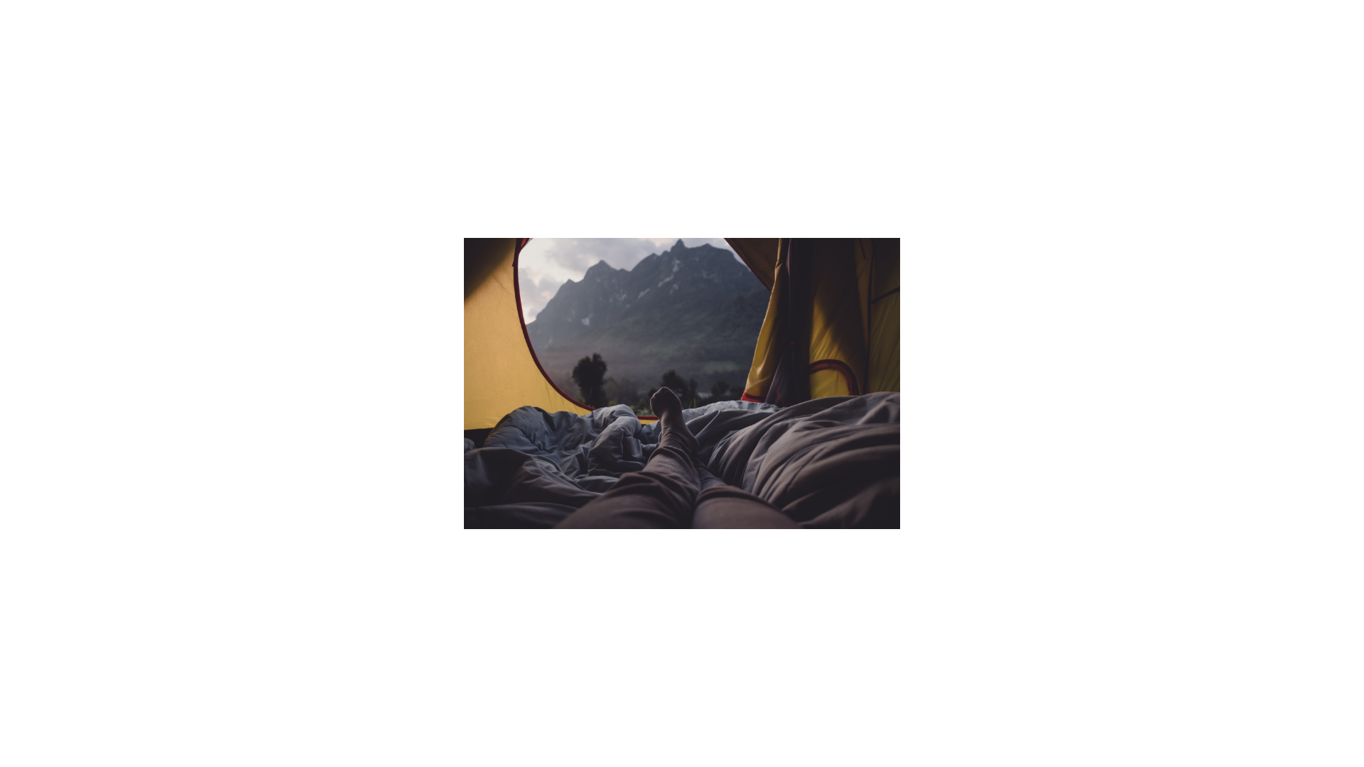 a person laying in a tent looking at a view of a mountain